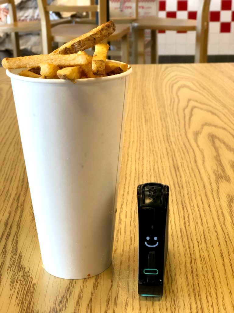 Five Guys french fries in a cup with a Nima Sensor smiling, indicating that the fries do not contain any hidden gluten