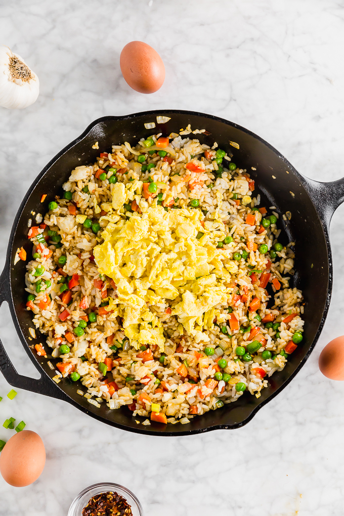 Picture of cooked scrambled eggs over fried rice skillet in progress