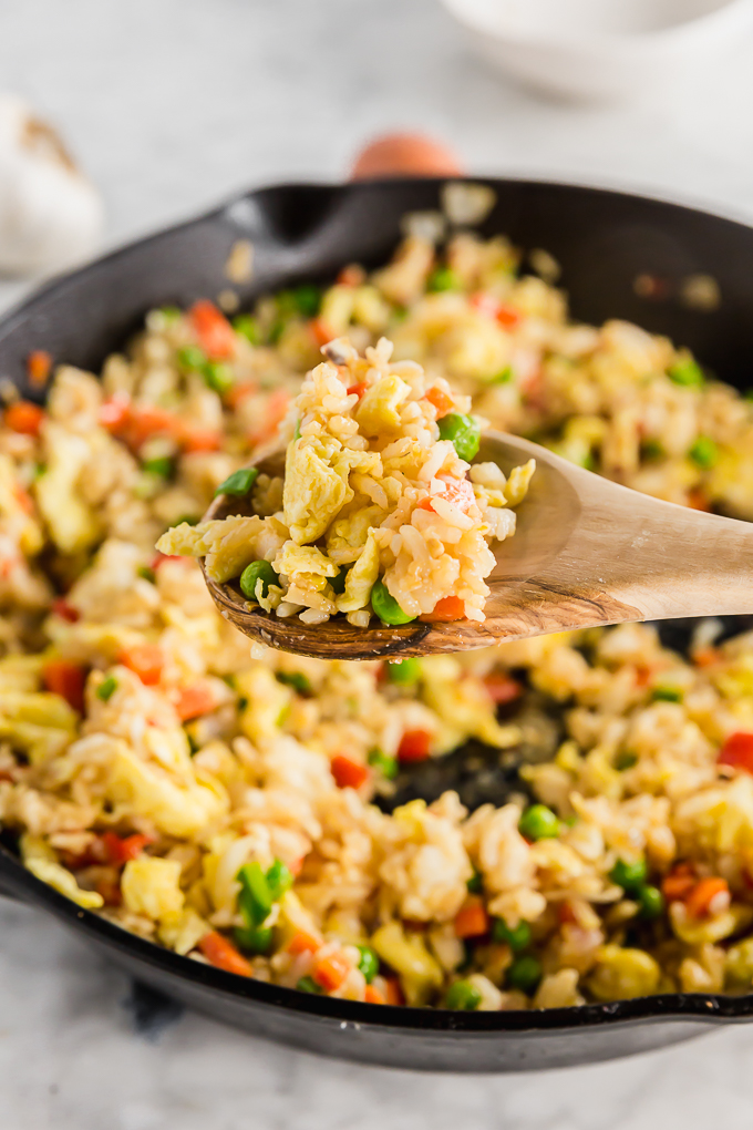 upclose picture of spoon of gluten-free egg fried rice over a skillet