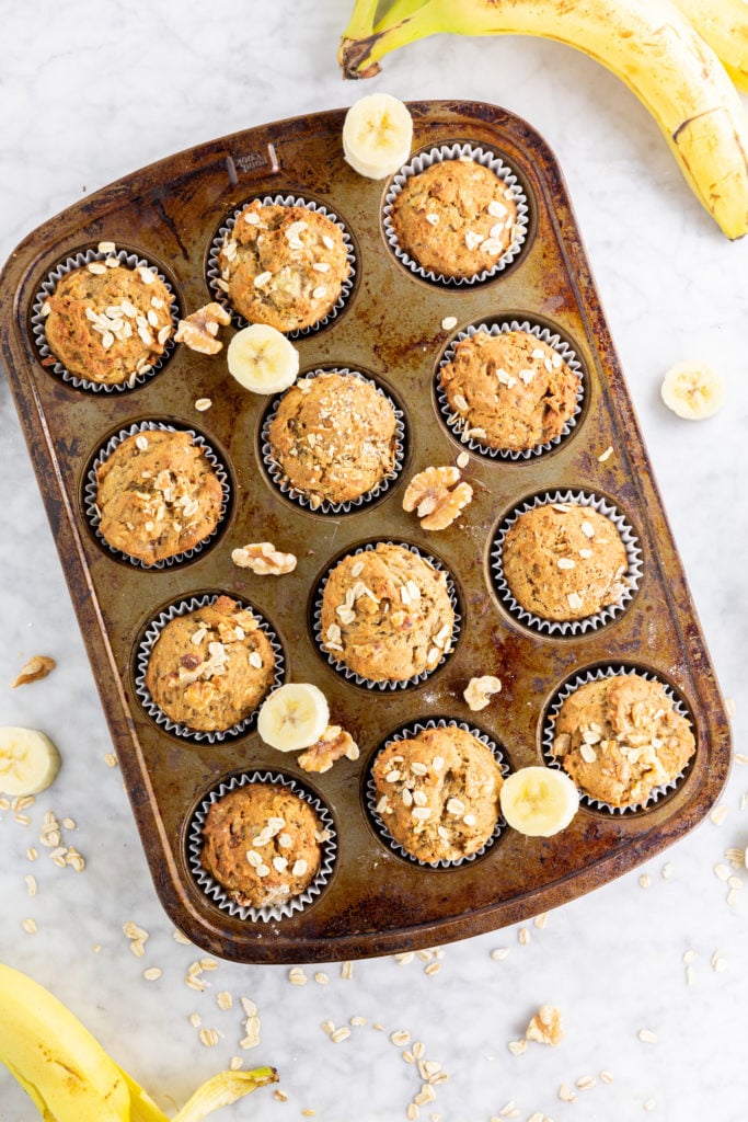 Banana walnut muffins in a tray with oats and bananas