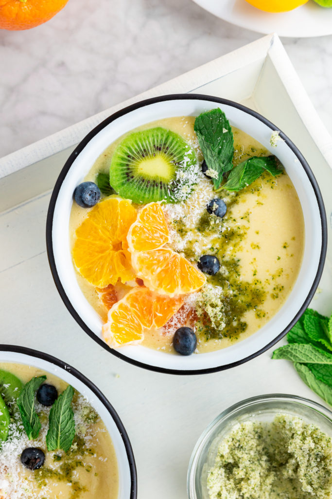 picture of tropical smoothie bowl topped with mint, kiwi, and oranges