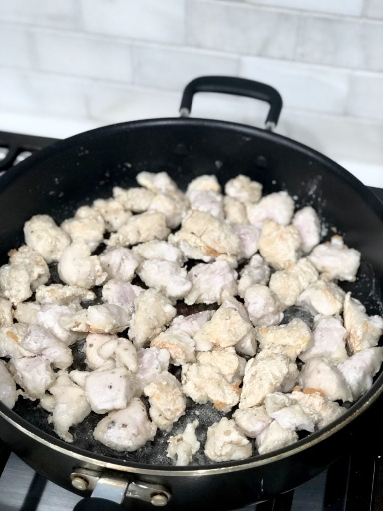 Chicken pieces cooking in a pan for gluten-free lemon chicken piccata bowls