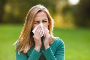 Picture of woman sneezing as header image for blog post about allergy testing