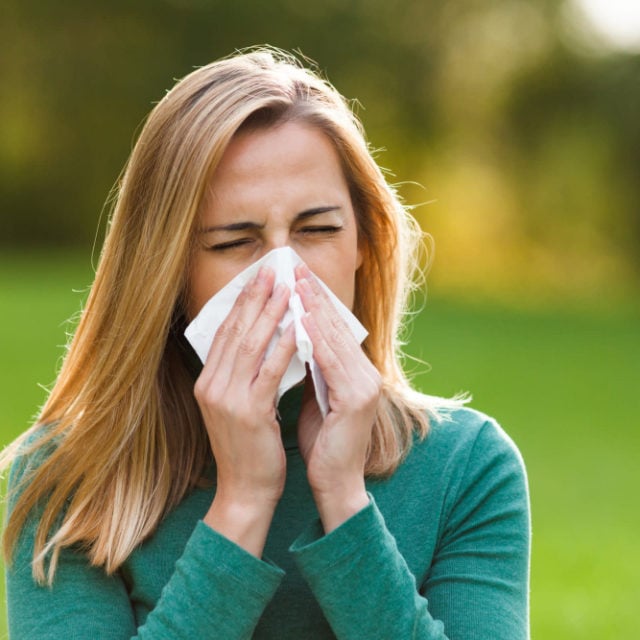 Picture of woman sneezing as header image for blog post about allergy testing