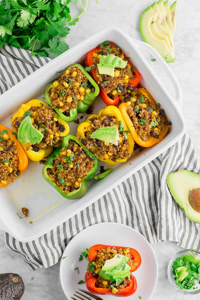 Picture of beef, quinoa, black bean and corn-stuffed bell peppers inside a casserole dish. Recipe by A Dash of Megnut.