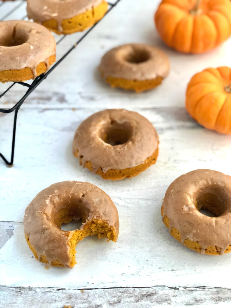 Picture of pumpkin donuts on table with a bite taken out of one of them