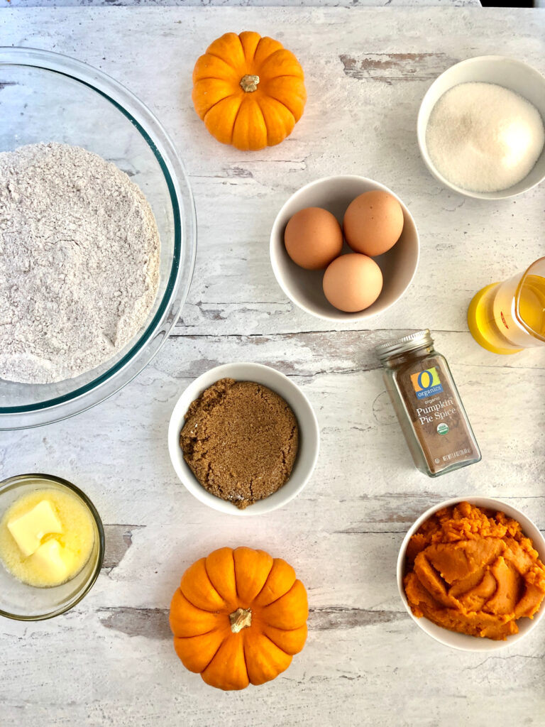 Ingredients for the pumpkin donuts including flour, pumpkin pie spice, brown sugar, butter, eggs and pumpkin puree.