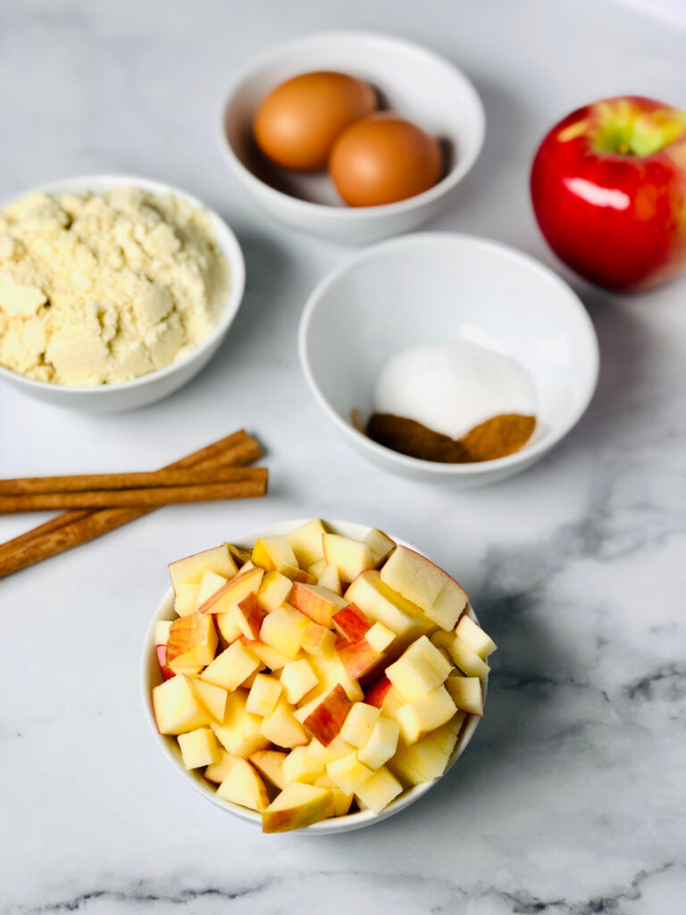 Picture of diced apples, cinnamon, sugar, almond flour and eggs - all the ingredients needed for the almond flour muffins