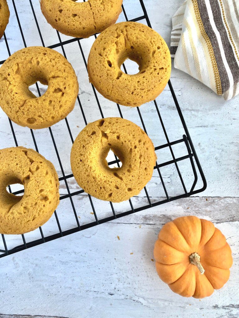 Spongy looking pumpkin donuts cooling on a wire rack
