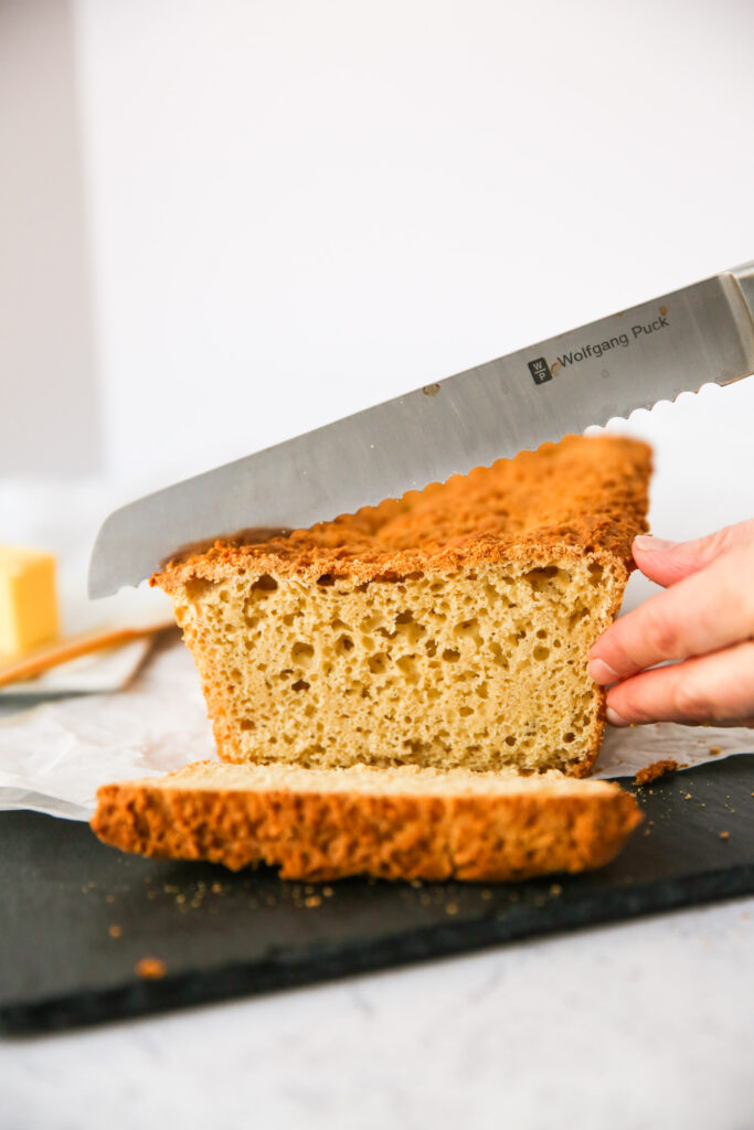 Gluten-free sandwich bread being cut with a serrated knife
