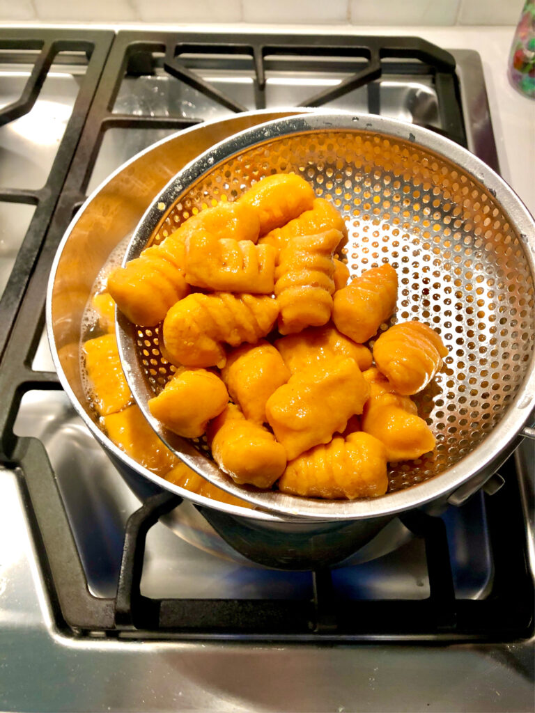 Gnocchi being removed from water with strainer