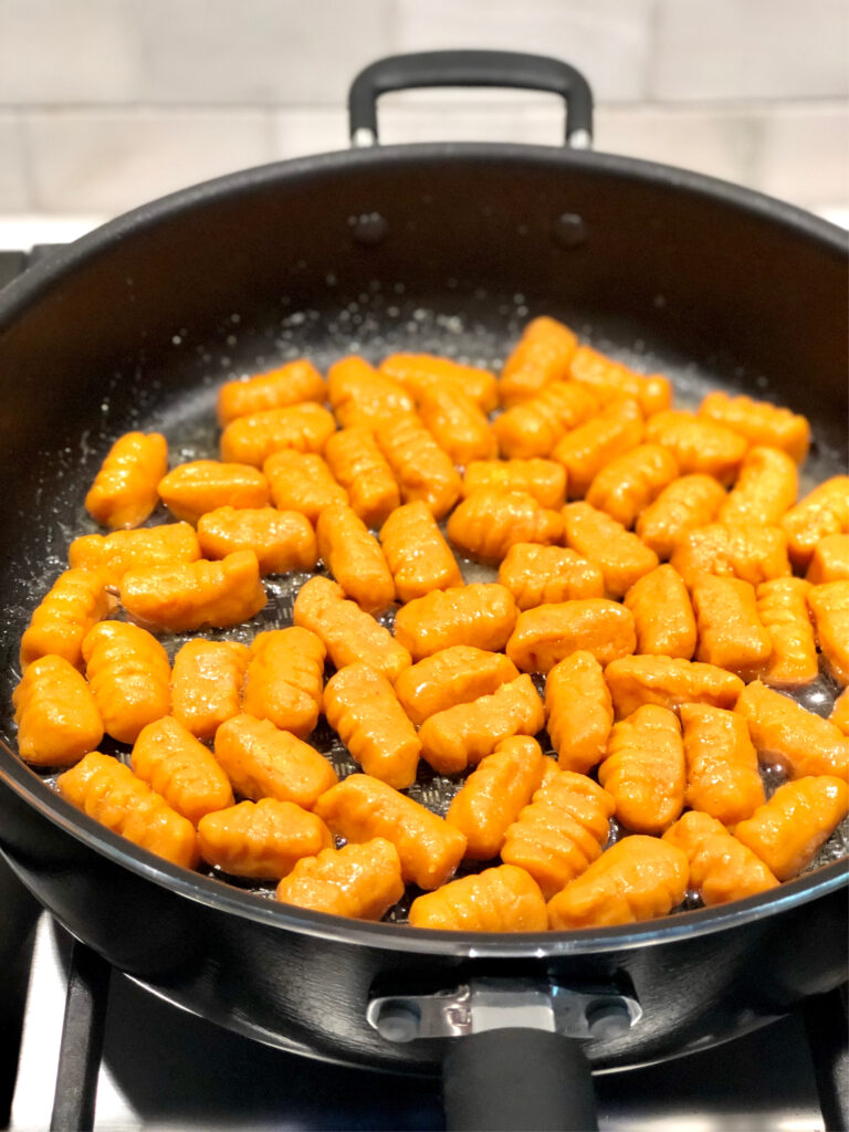 Gnocchi being cooked in a pan with butter.