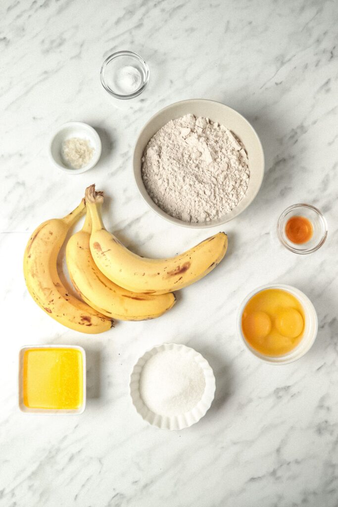 Overhead picture of bananas, eggs, butter, flour and other ingredients for the banana bread