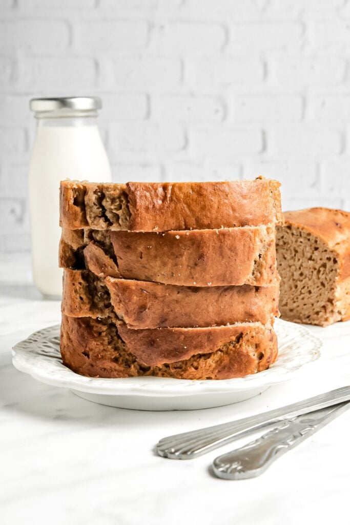 Large stack of banana bread slices with milk in background.