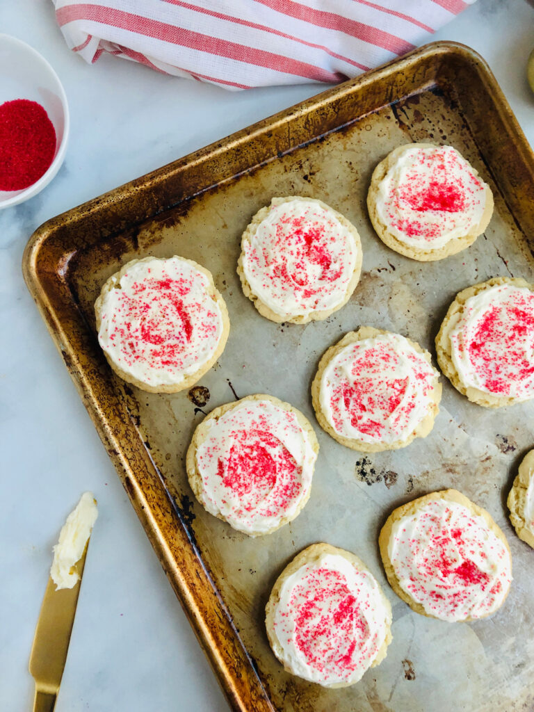 Cookies on a baking tray frosted and sprinkled with red decorating sugar