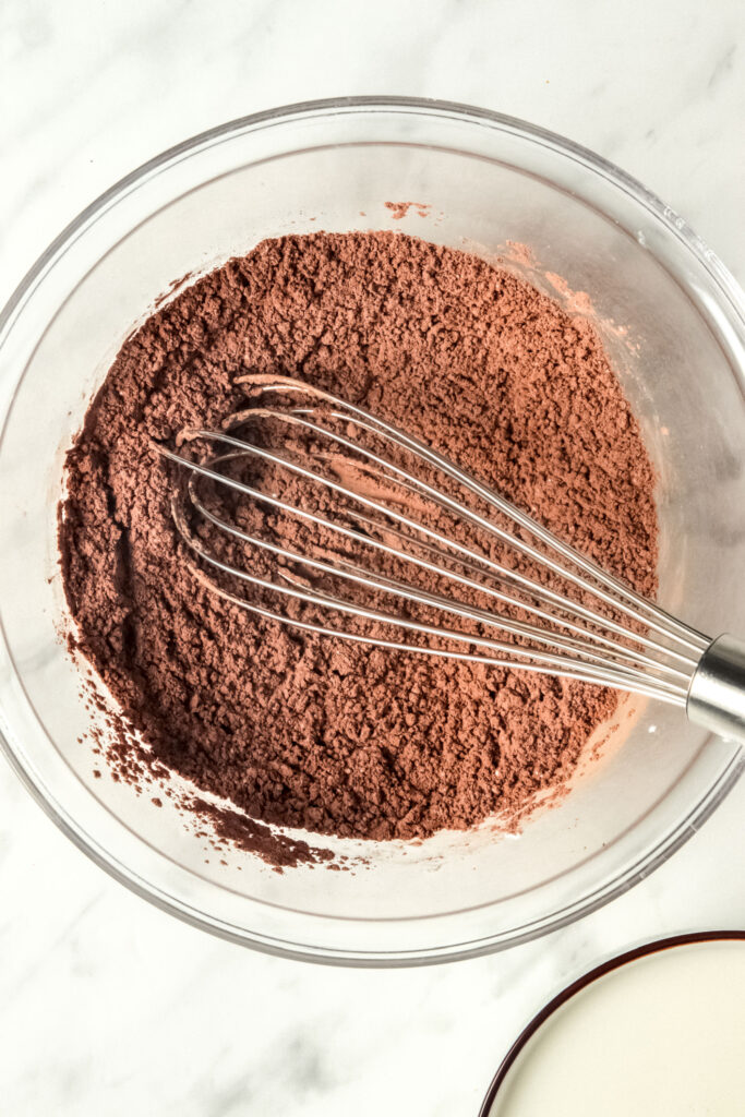 Dry ingredients in a bowl, including cocoa powder and cornstarch. Whisk is mixing it together