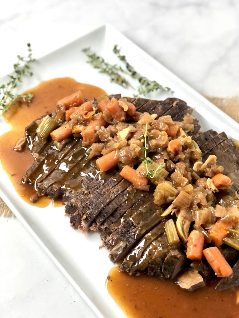 Savory beef brisket on a platter smothered with veggies