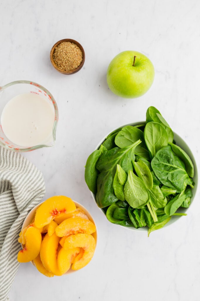 Picture of a green apple, spinach, milk and peaches.