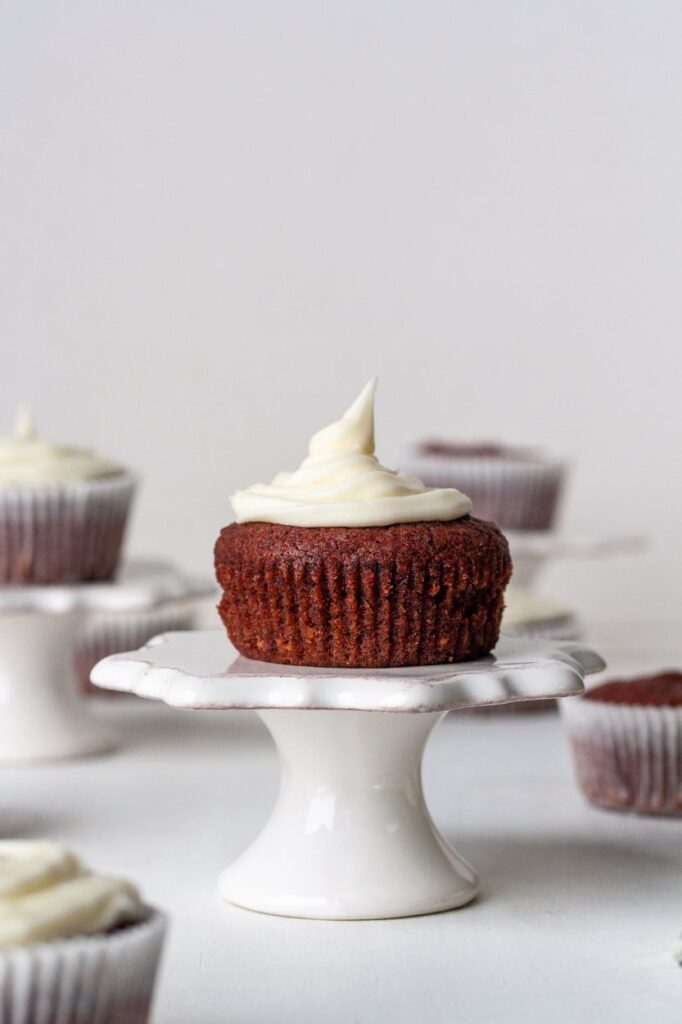 Picture of frosted gluten-free red velvet cupcake on pedestal  