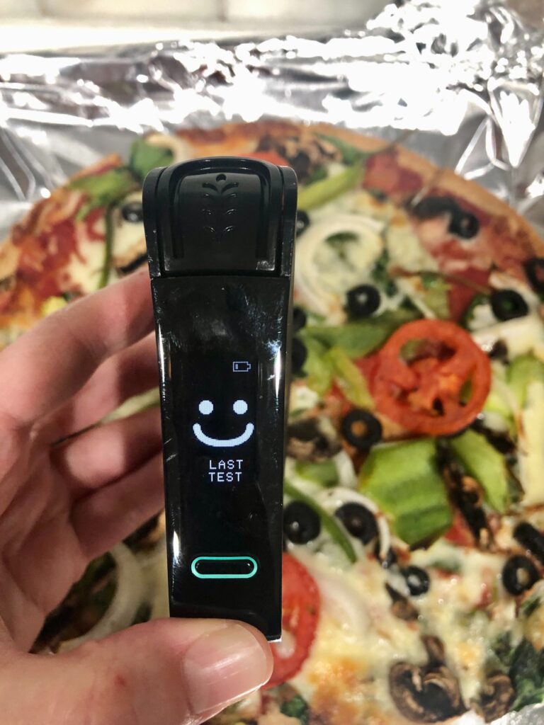 Picture of smiling face on Nima Sensor over Mellow Mushroom gluten-free pizza pie