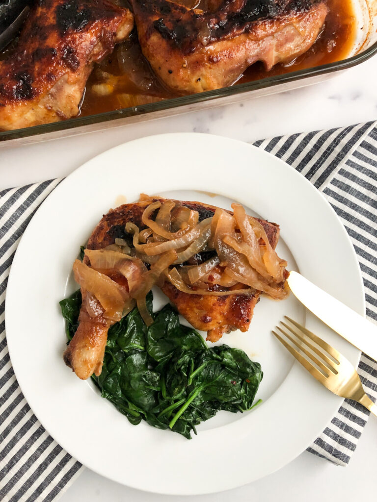 Picture of plated BBQ Coke Chicken with onions on top and served with spinach