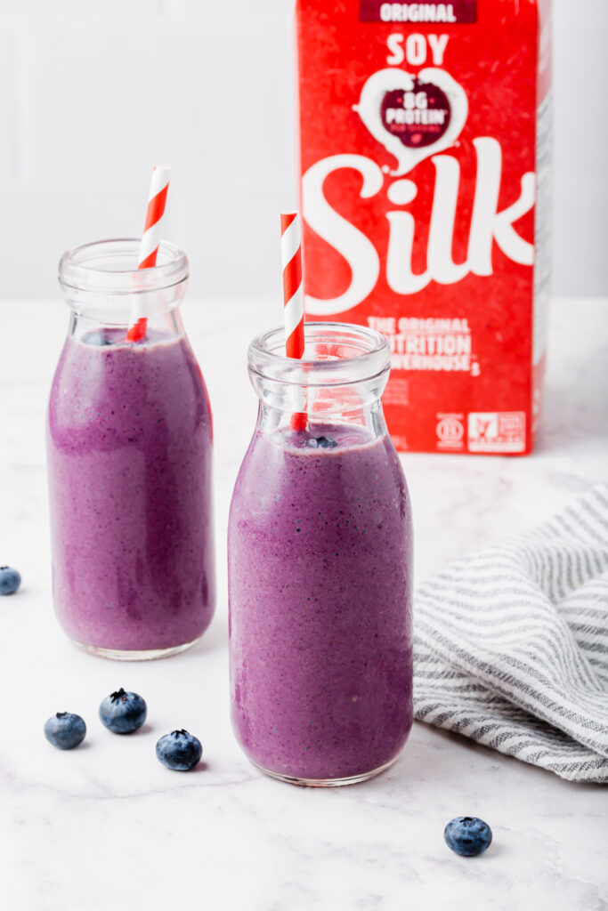 Two blueberry banana smoothies in jars with Silk container in background