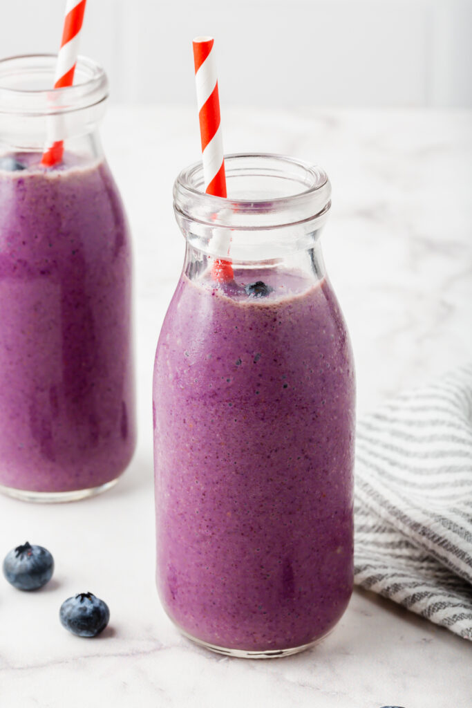 Two beautiful jars of blueberry banana smoothies with extra blueberries for garnish