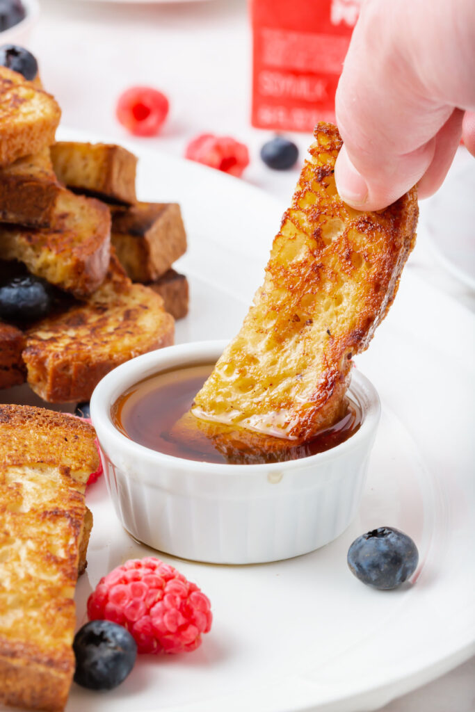 dipping a gluten-free french toast stick in maplesyrup