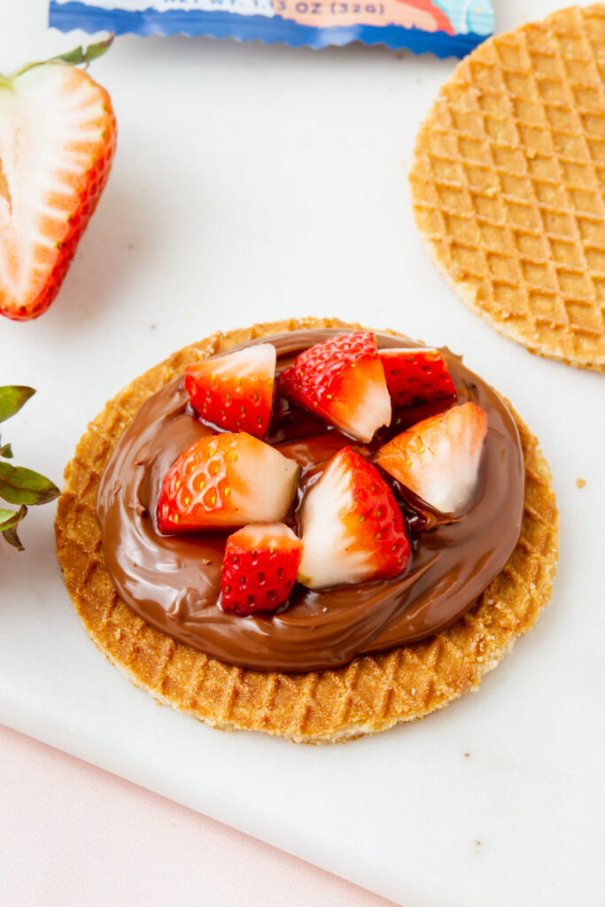 gluten-free stroopwafel covered with chocolate spread and chopped strawberries