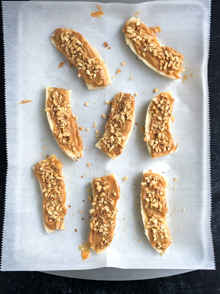 Bananas coated in peanut butter and crushed peanuts