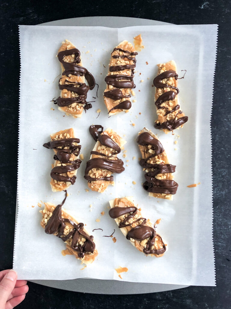 Tray of healthy Snickers drizzled with chocolate and ready for the freezer