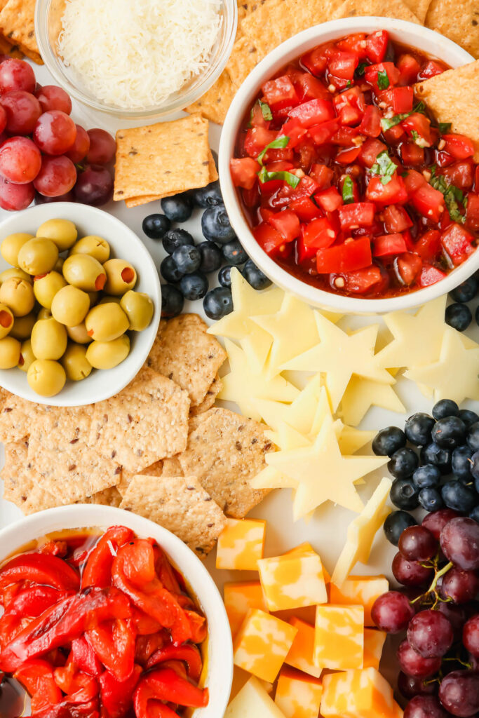 Upclose picture of 4th of July snack board with star-shaped cheeses, fruits and vegetables.