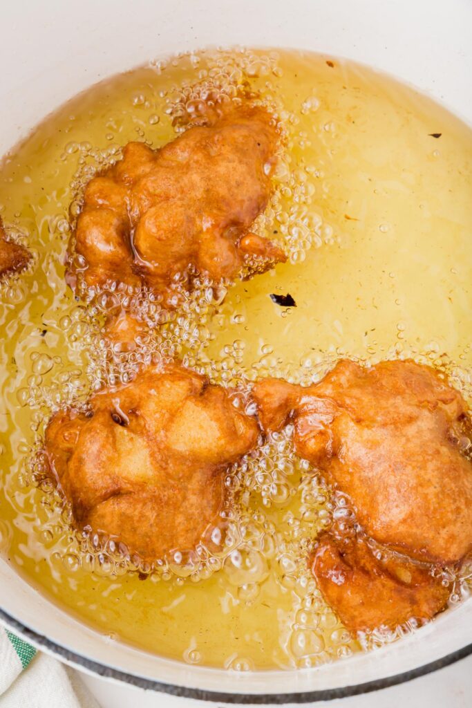 Apple fritters browning in oil in a pan
