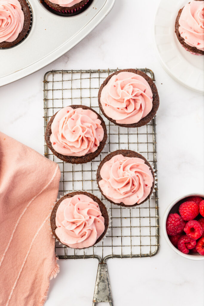 gluten-free chocolate cupcakes with raspberry buttercream frosting on a table