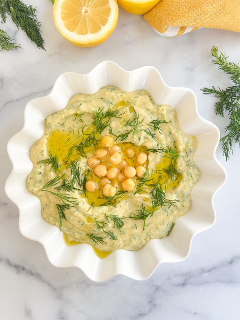 Lemon dill hummus in a bowl topped with olive oil and dill