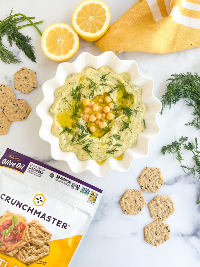 Lemon dill hummus in a bowl with Crunchmaster Crackers
