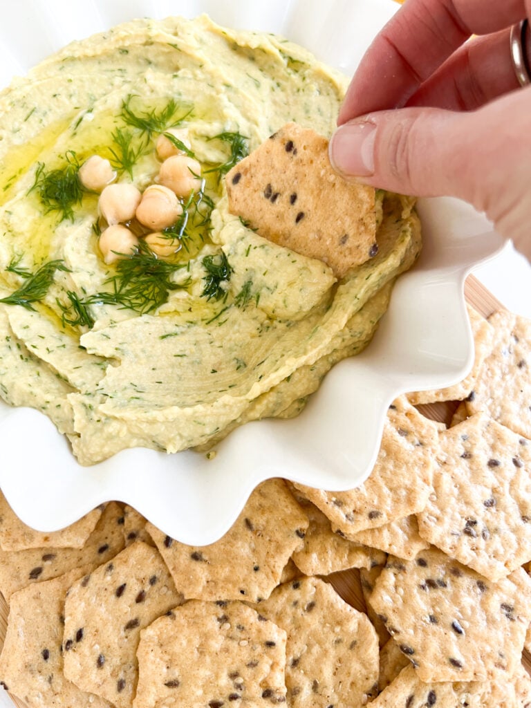 dipping cracker in lemon dill hummus