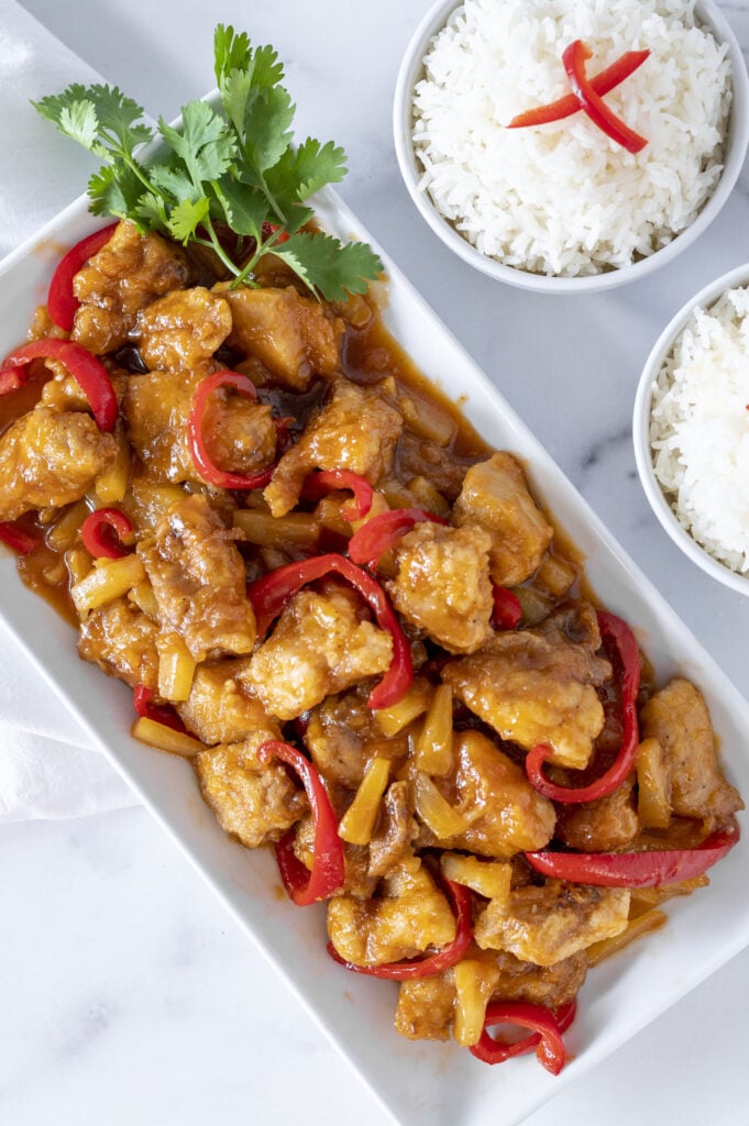 the sweet and sour chicken on a plate ready to serve with rice bowls