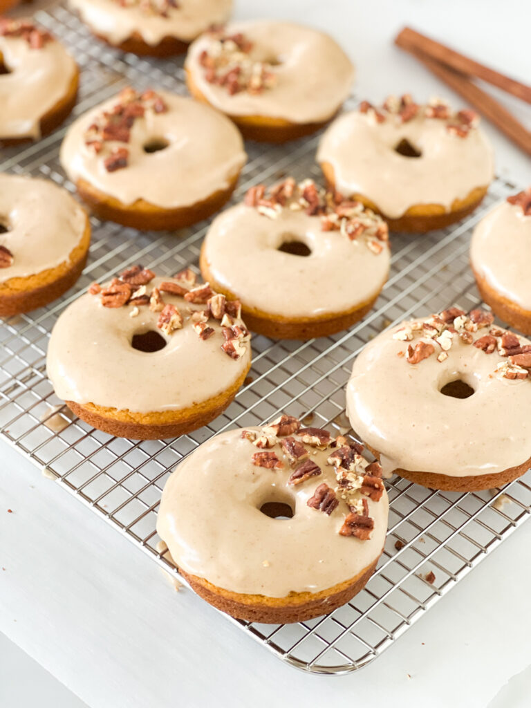 pumpkin donuts with maple glaze and nuts on top on wire rack