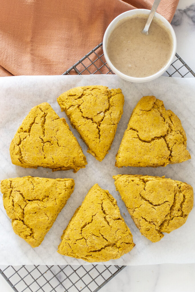 gluten-free pumpkin scones with glaze in a bowl ready to drizzle on top
