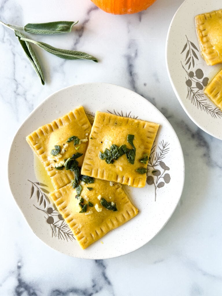 gluten-free pumpkin ravioi on a plate with sage butter topping