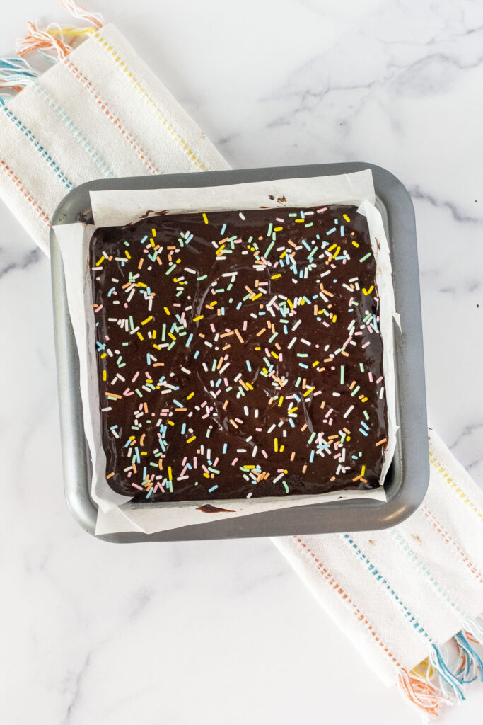 Cosmic brownies in a pan coated with fudge and sprinkles