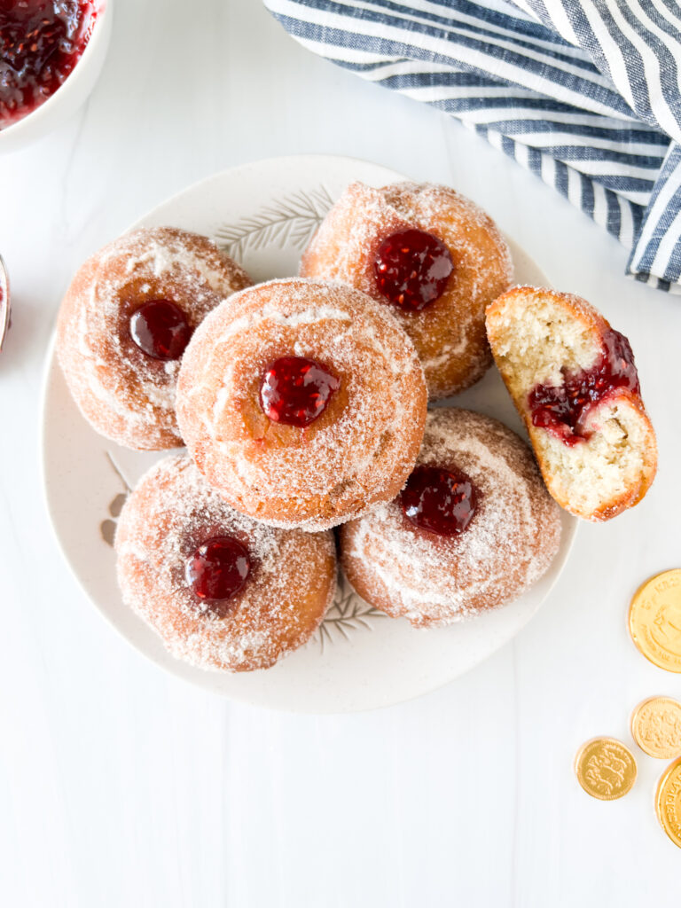 gluten-free jelly donuts stacked on a plate with chocolate coins